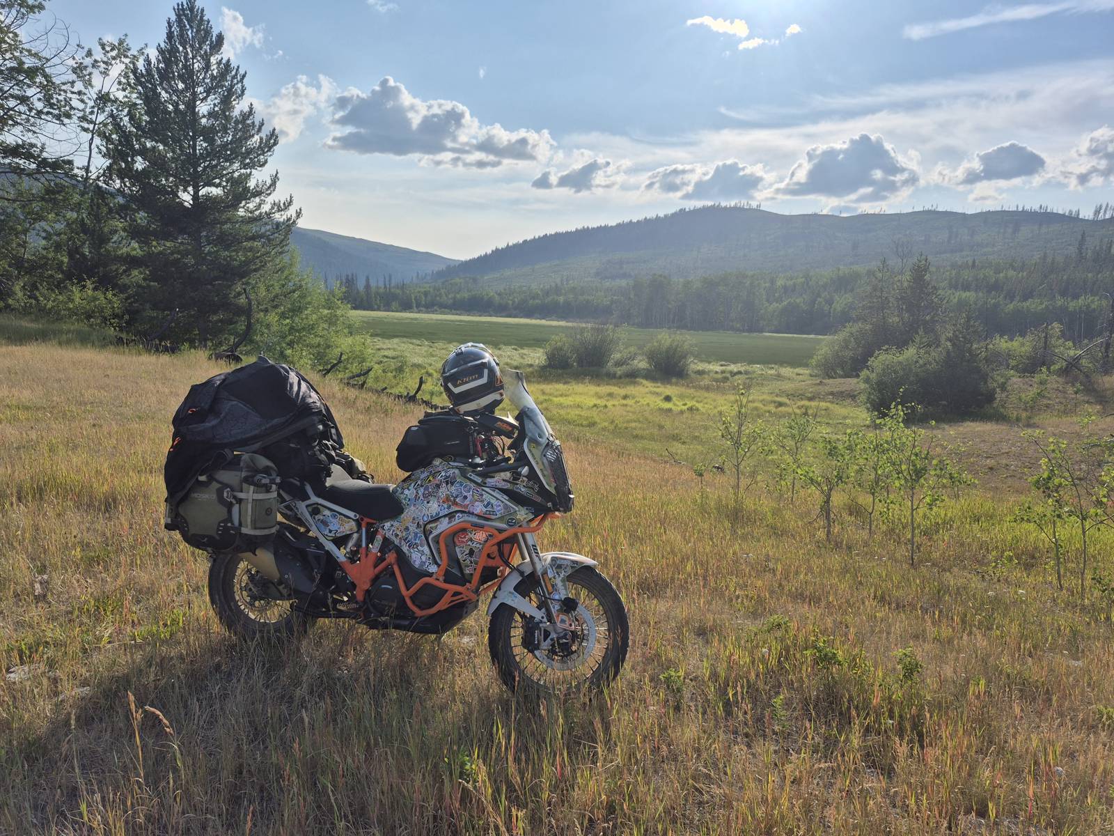 Loaded adventure motorcycle parked in a mountain meadow at golden hour